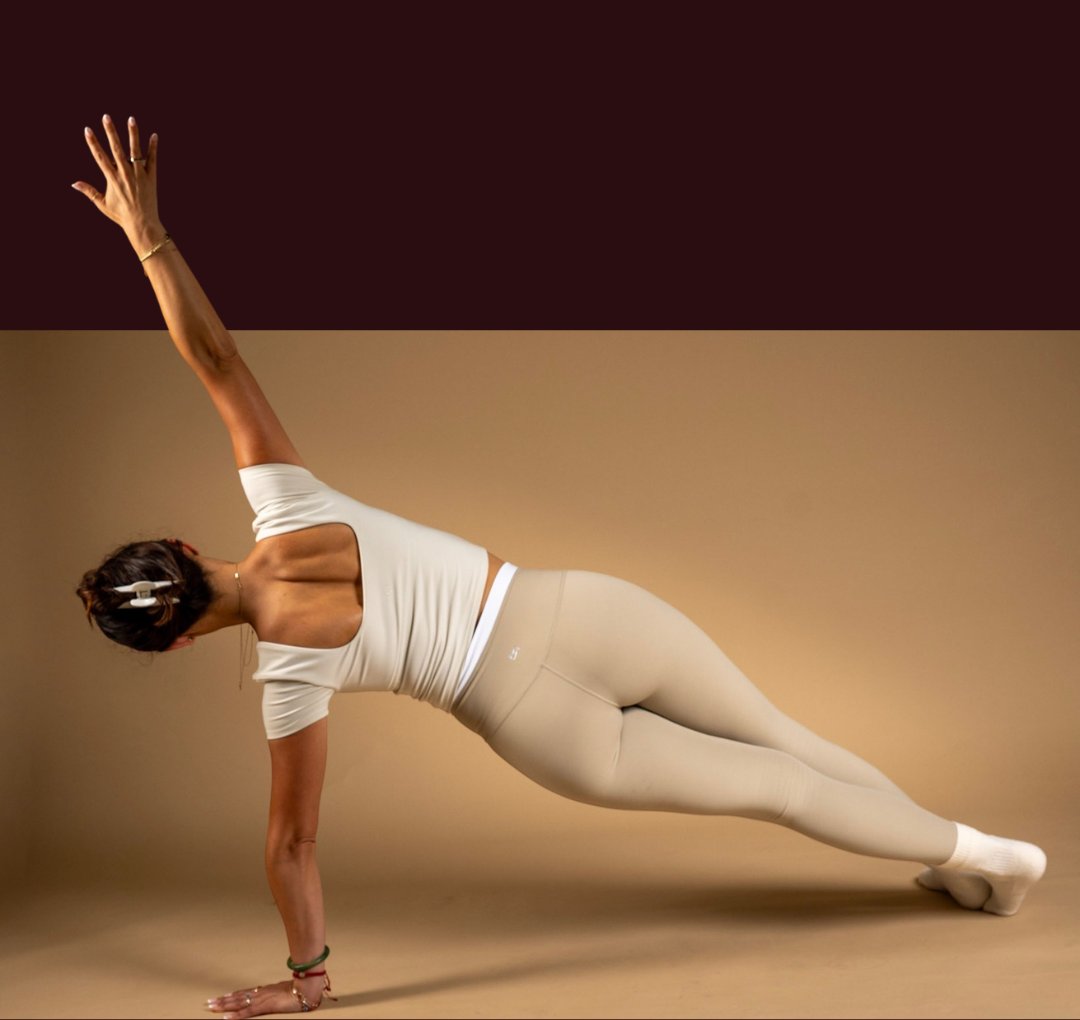 An instructor holding a side plank with one arm reaching upward